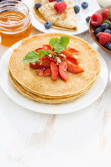 Delicious crepes with strawberries and honey on white