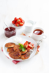 Fototapeta na wymiar Delicious pancakes with fresh strawberries, jam and tea on white