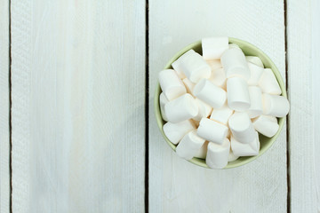 marshmallows in a bowl on wooden background