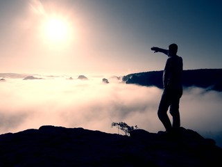 Man stand on peak of rock empire and watch into nature miracle 