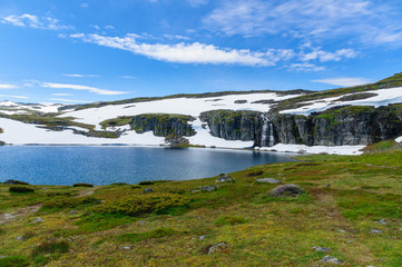 Highland norwegian summer landscape with lake and snow
