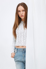 Portrait of young woman standing against curtains.