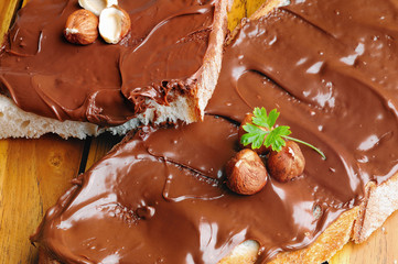 Bread with chocolate cream and hazelnuts on table closeup top