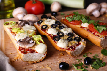 Different sandwiches with vegetables and cheese on cutting board on table close up