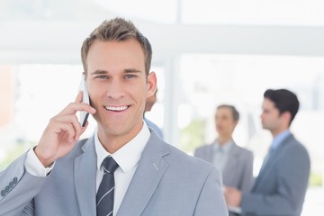 Businessman having phone call while his colleagues discussing