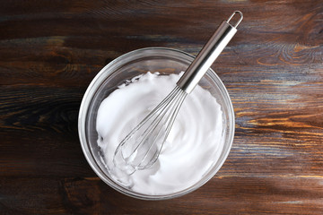 Whipped egg whites for cream on wooden table, top view