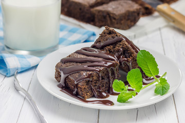 Homemade brownies with chocolate sauce and glass of milk