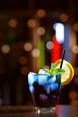 Glass of cocktail in bar on bright blurred background