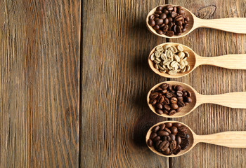 Coffee beans in spoons on wooden background