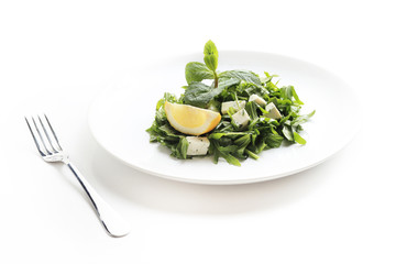 Green salad with cheese, lettuce, mint, rucola and lemon isolated on white