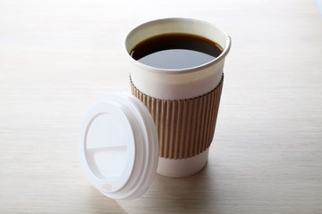 Paper cup of coffee on wooden background
