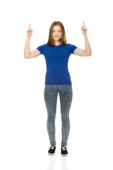 Obraz premium Smiling young woman pointing up.