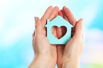Fototapeta premium Female hands holding model of house on bright background
