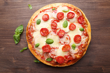 Delicious pizza with cheese and cherry tomatoes on wooden table, top view