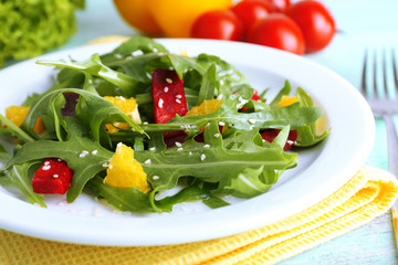 Tasty salad with arugula leaves in plate on wooden table, closeup