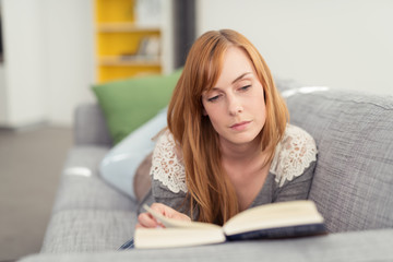 frau entspannt mit einem guten buch auf dem sofa