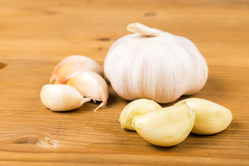Peeled garlic cloves with garlic bulb and cloves as background