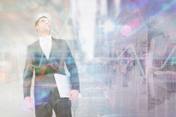 Composite image of businessman looking up holding laptop