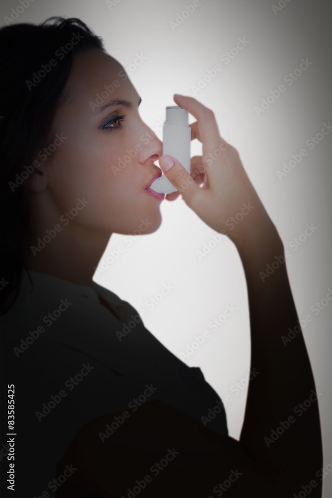 Poster composite image of asthmatic brunette using her inhaler