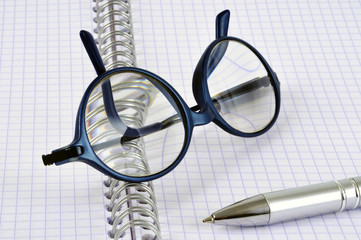 Lunettes et stylo posés sur un cahier à spirales