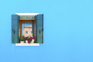  Decorated window on the blue wall on Burano island, Venice