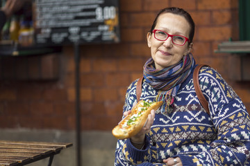 Obraz premium Woman eating Zapiekanka - Polish fast-food a casserole.