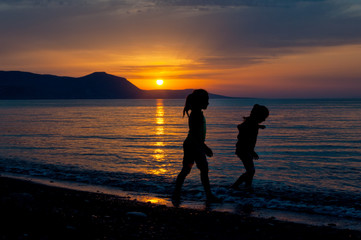 Two girls walking along the beach during sunset