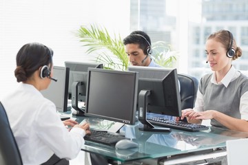 Fototapeta na wymiar Business people with headsets using computers 
