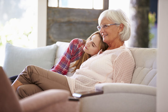Grandmother With Adult Granddaughter Watching TV On Sofa