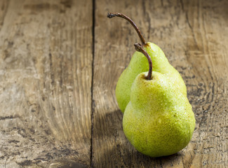 Two fresh green pear with drops of water on wooden table, select