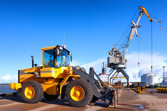 Orange forklift and crane at loading and unloading of cargo in t