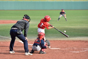 少年野球の試合でヒットを打つバッター