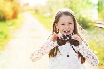 Lachendes Mädchen mit Fernglas im Sommerlicht