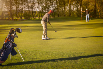 Two senior golfer playing golf at dusk.