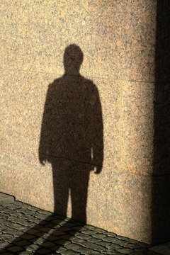 Shadow of person on the stone wall at sunset time