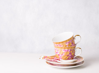 two vintage cups, sauceres and spoons on a white background