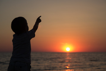 Fototapeta premium little boy standing back and watching the sunset
