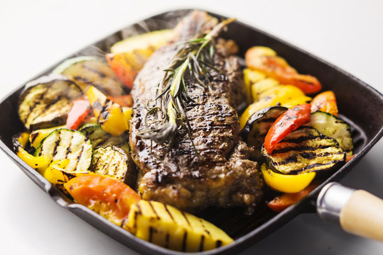beef steak with grilled vegetables in skillet