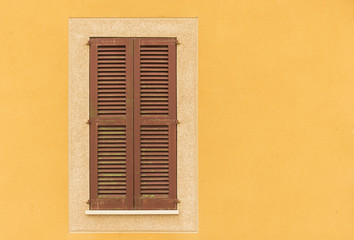 Fototapeta premium Braune Fensterläden geschlossen mit gelber Fassade