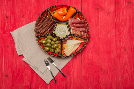 Basket with several Spanish tapas on red table
