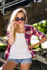 Trendy hipster girl standing on stairs looking over sunglasses