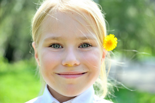 Pretty blone girl outdoors with flower behind ear