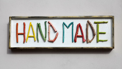 Sign with colorful wooden letters forming word "hand made"