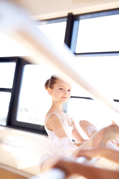 Pretty Ballet Girl Stretching her Leg Using a Bar