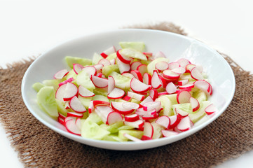 Fresh salad in plate at sackcloth on white background. Not