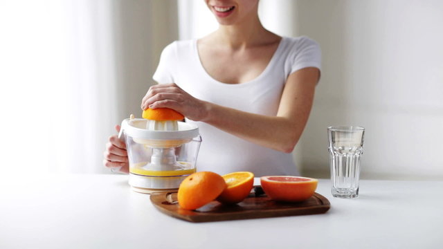 woman with squeezer squeezing orange juice at home