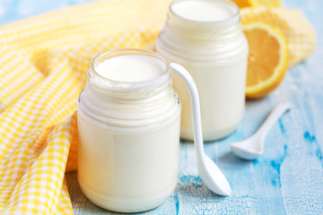 Obraz na płótnie Canvas Homemade yogurt in two small glass jars on a blue table