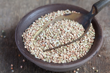 Dry green buckwheat in a clay bowl and in a scoop 