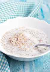 Green buckwheat porridge with milk on wooden table