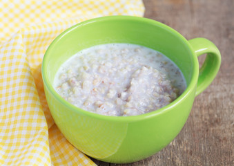 Green buckwheat porridge with milk on wooden table